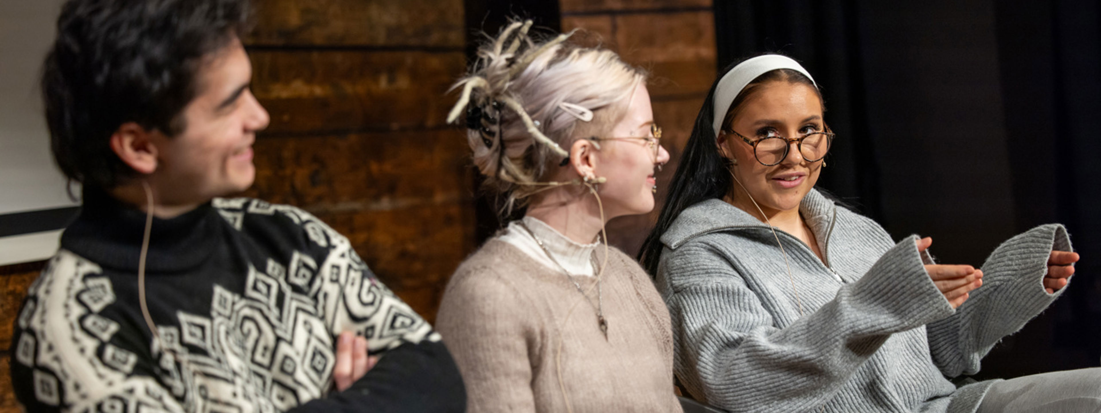 Tre personer sitter på en scene og snakker