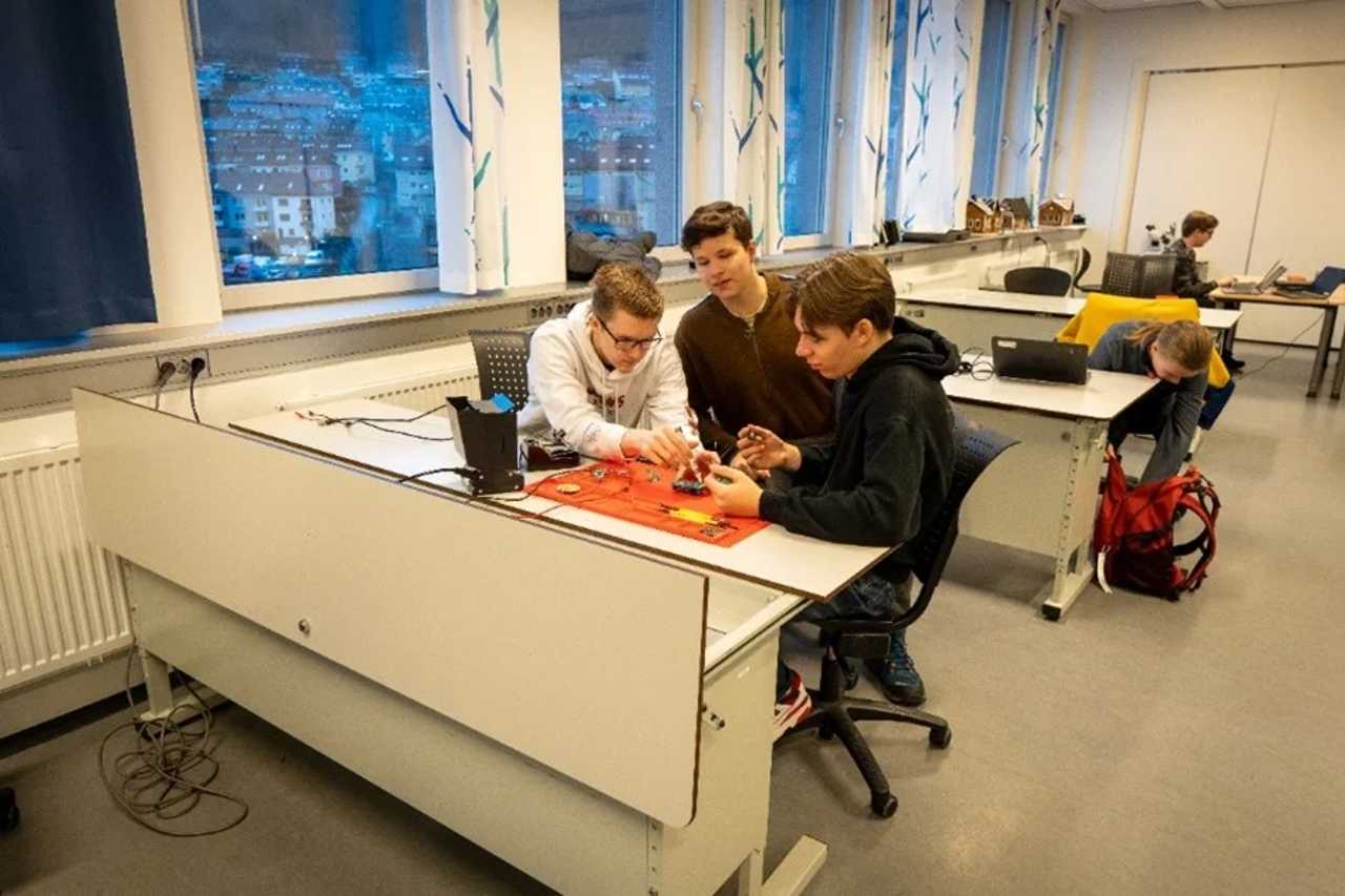 Tre elevar sitt i lag og skrur på datakomponentar