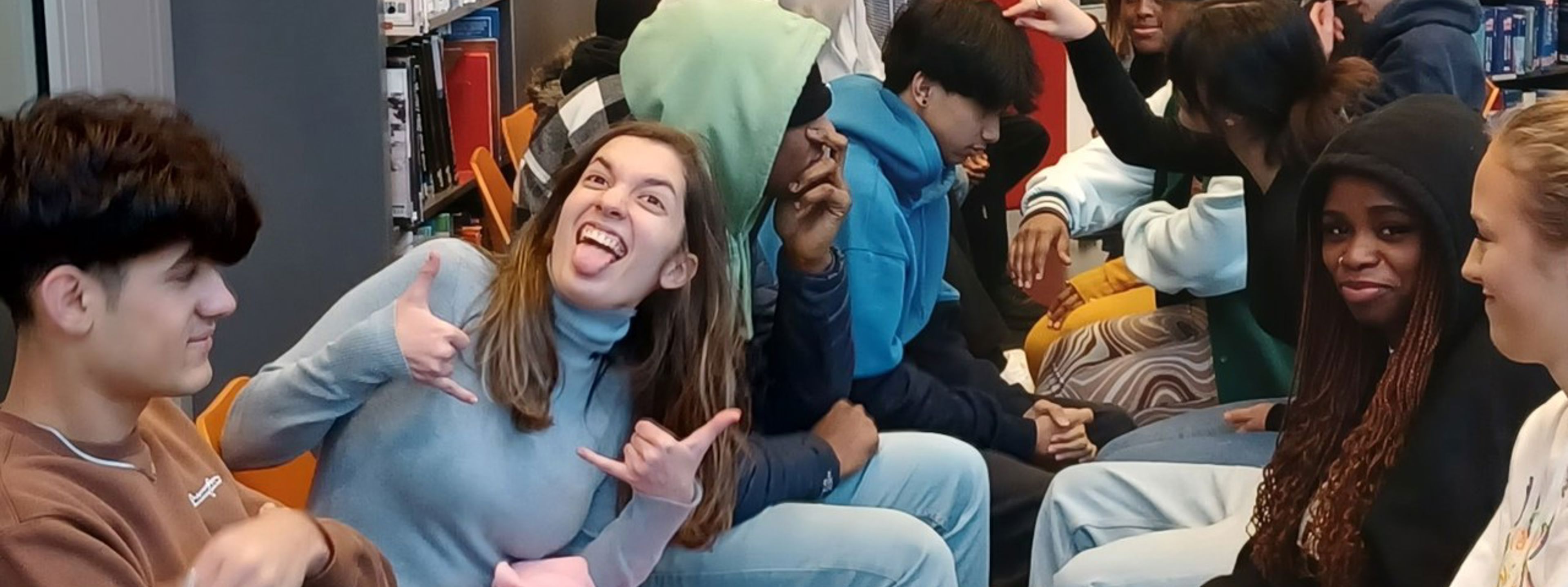 Elev lager grimaser sammen med mange glade elever på språkkafe'