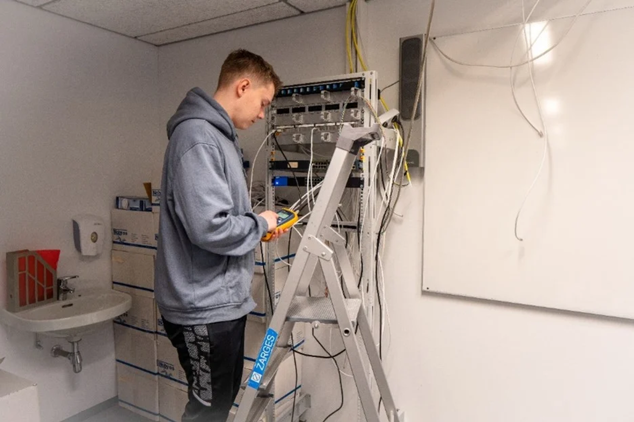 Elev i gardintrapp jobber med koplinger på vegg.