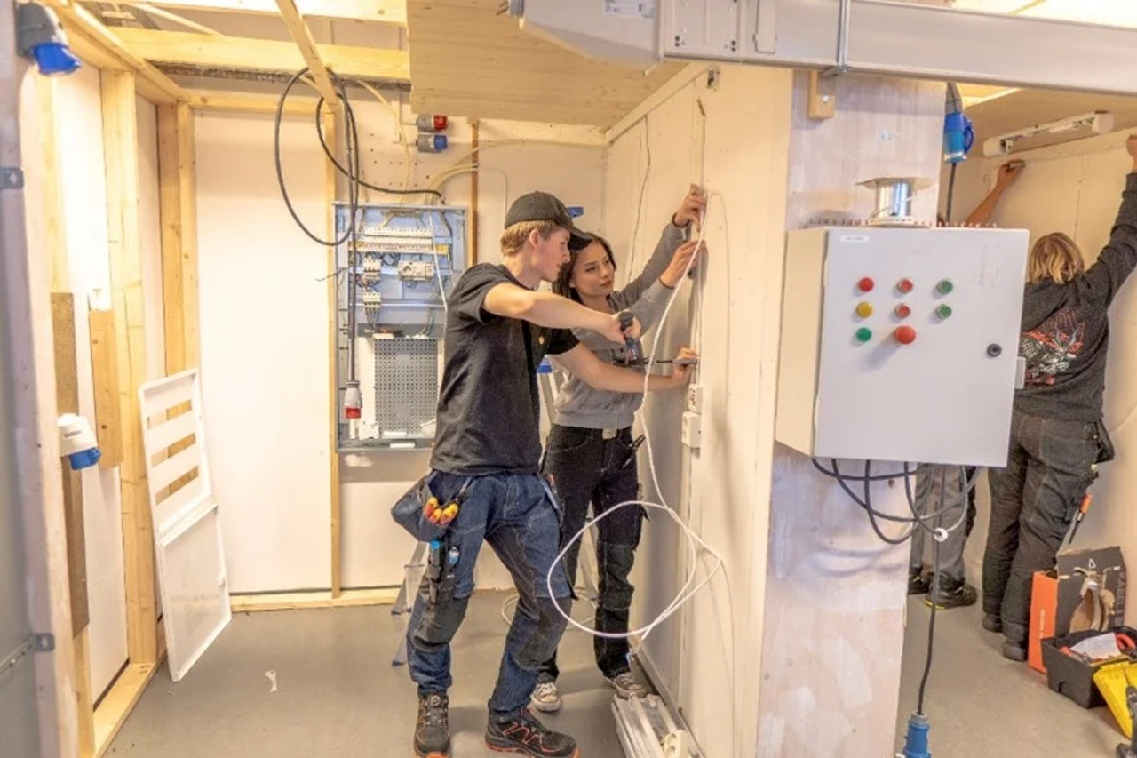 To elevar samarbeider om å henge opp kabel på verkstedet