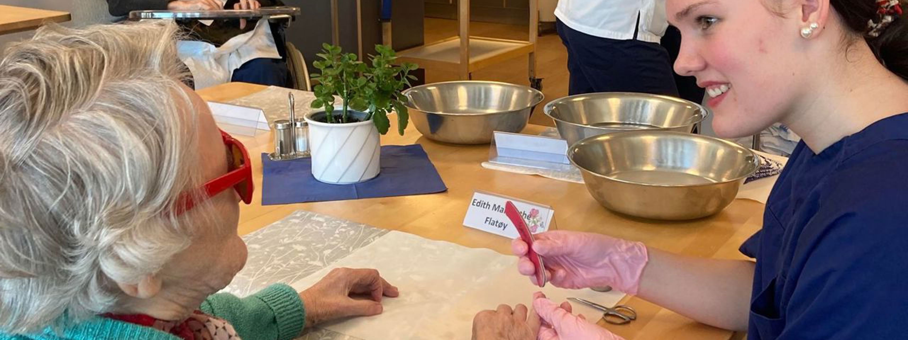 Hudpleieelev pleier hendene til beboer på pleiehjem