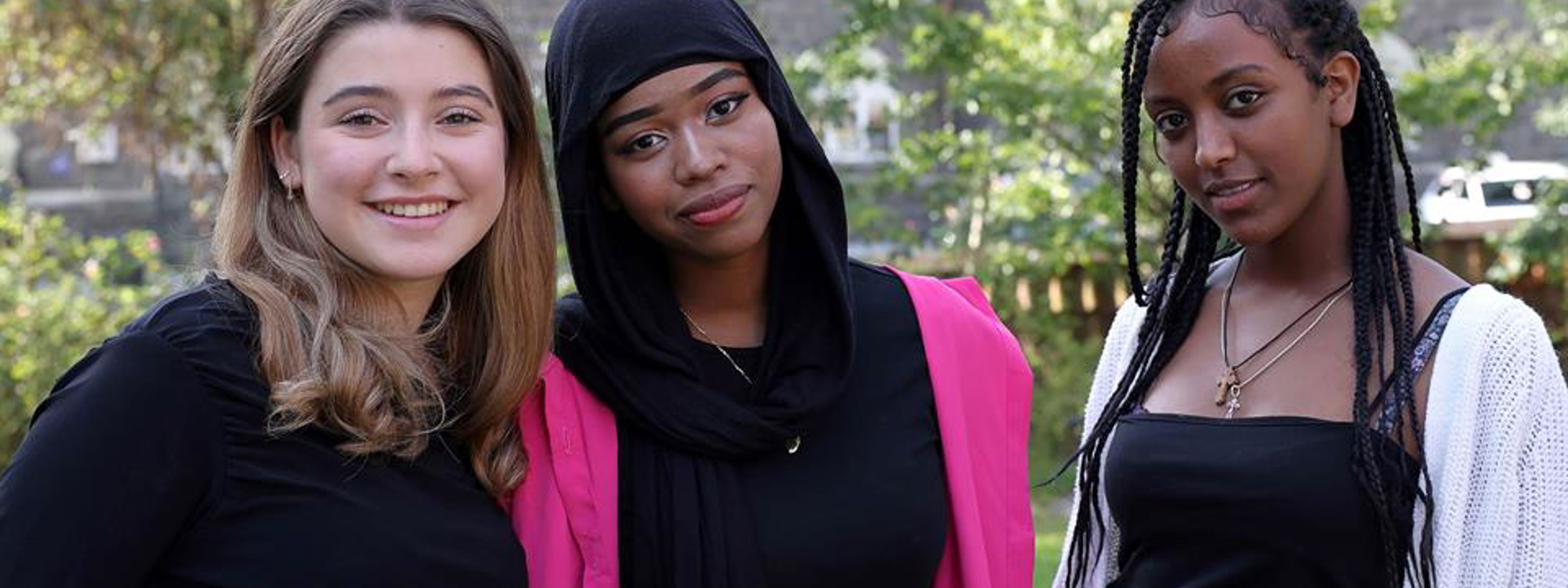 Tre jenter ved siden av hverandre som ser inn i kamera.