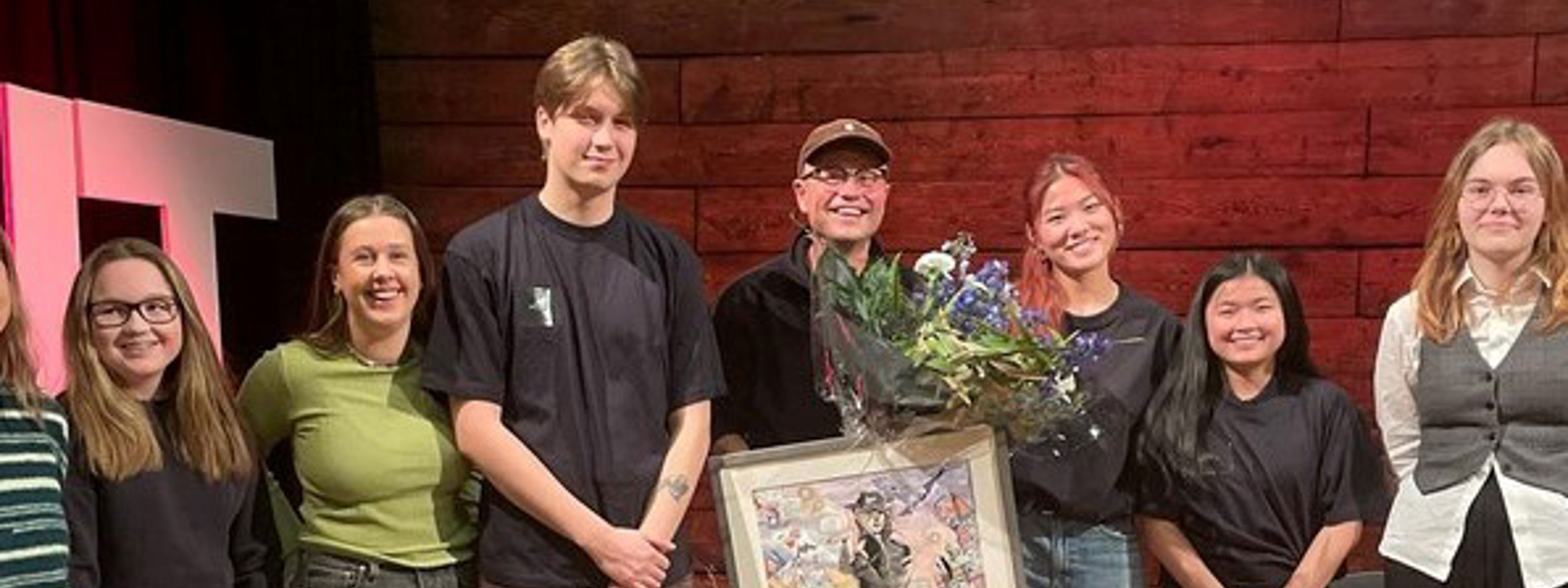 Smilende prisvinner sammen med syv jurymedlemmar 